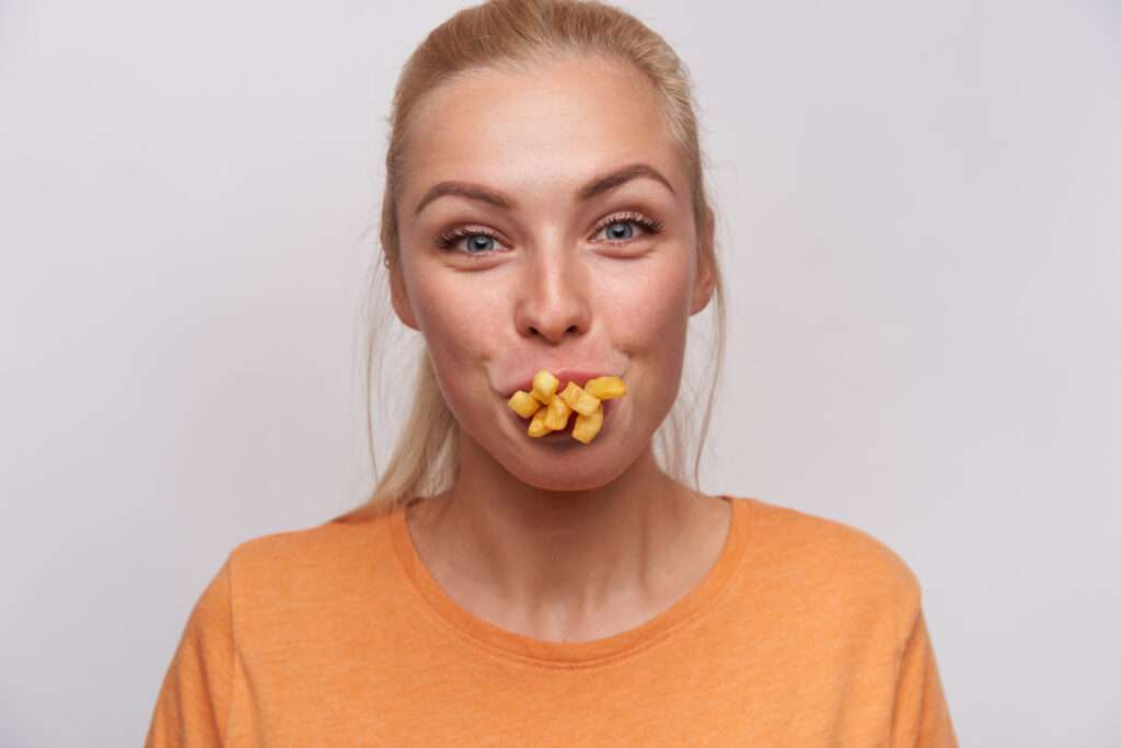 frietkar frietjes in mond van vrouw met een oranje shirt